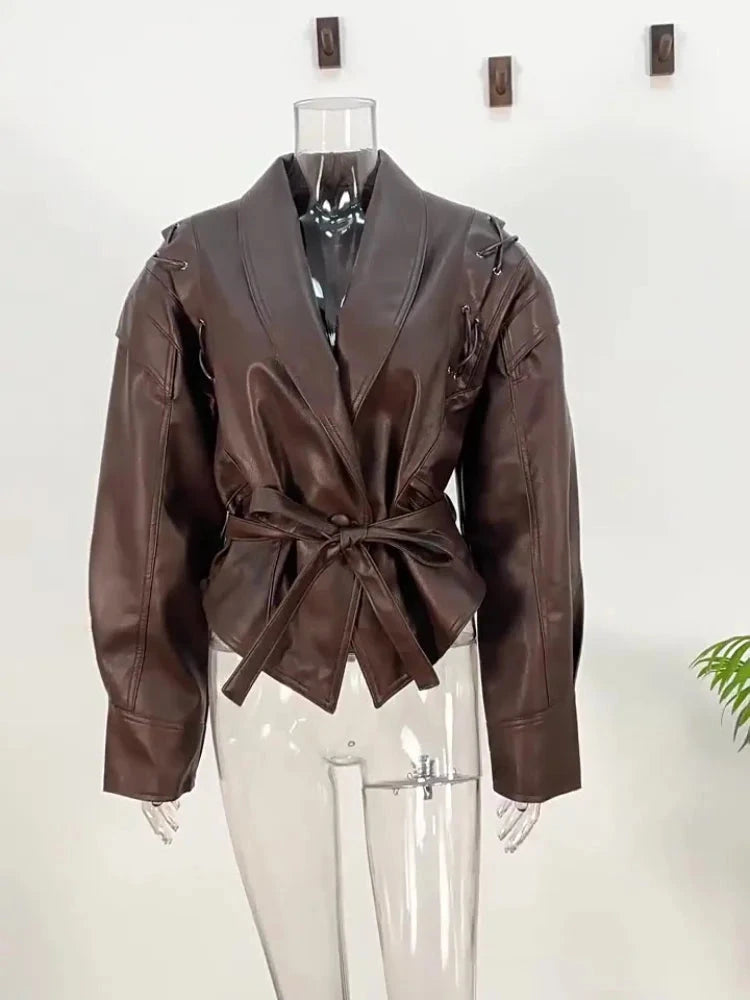 Vintage brown leather jacket with padded shoulders, belt closure, pockets, and turn-down collar.
