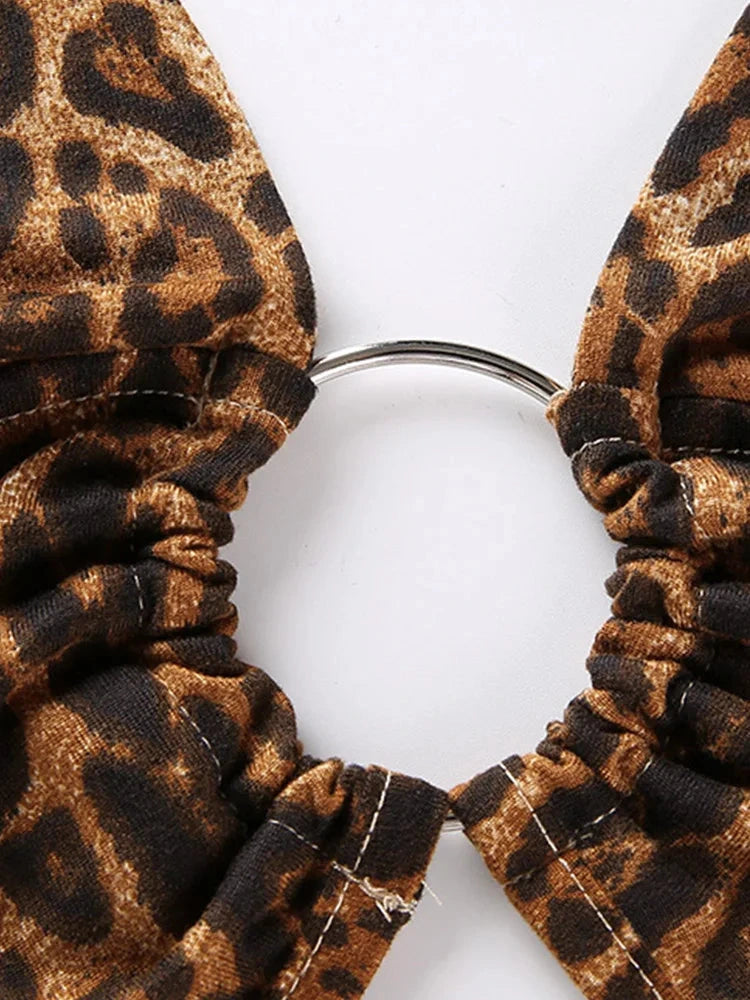 Leopard print halter crop top with backless design and metallic ring detail, made from lightweight polyester fabric.