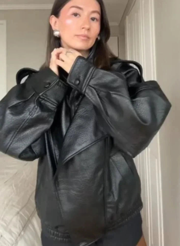 Black loose PU leather jacket with a front zipper and side pockets, displayed on a hanger against a neutral background.