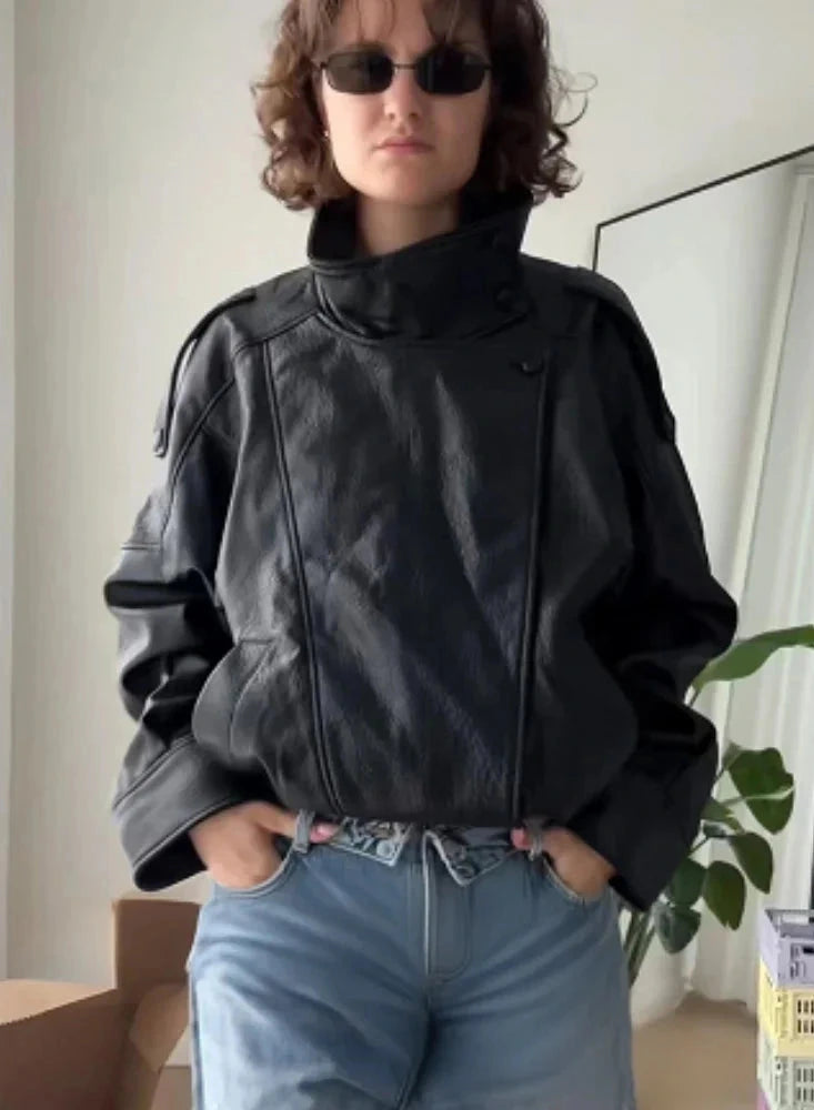 Loose black PU leather jacket with a relaxed fit and zippered front, displayed on a hanger against a neutral background.