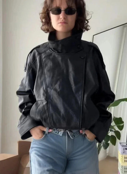 Loose black PU leather jacket with a relaxed fit and zippered front, displayed on a hanger against a neutral background.