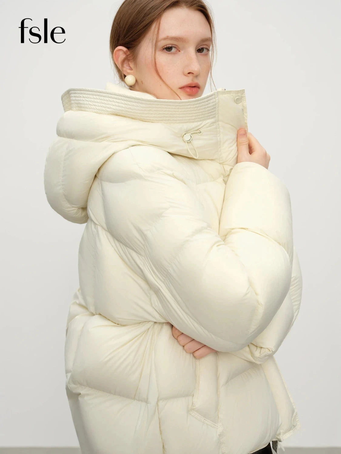 Contemporary short hooded puffer jacket with bat sleeves and duck down filling for warmth and comfort.