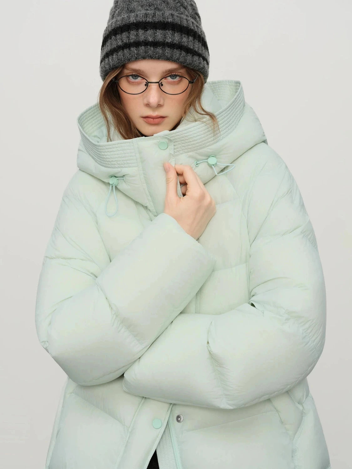 Contemporary short hooded puffer jacket with bat sleeves and duck down filling for warmth and comfort.