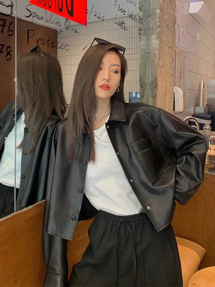 Chic short deep black faux leather jacket with a loose fit, single-breasted design, and functional pockets.