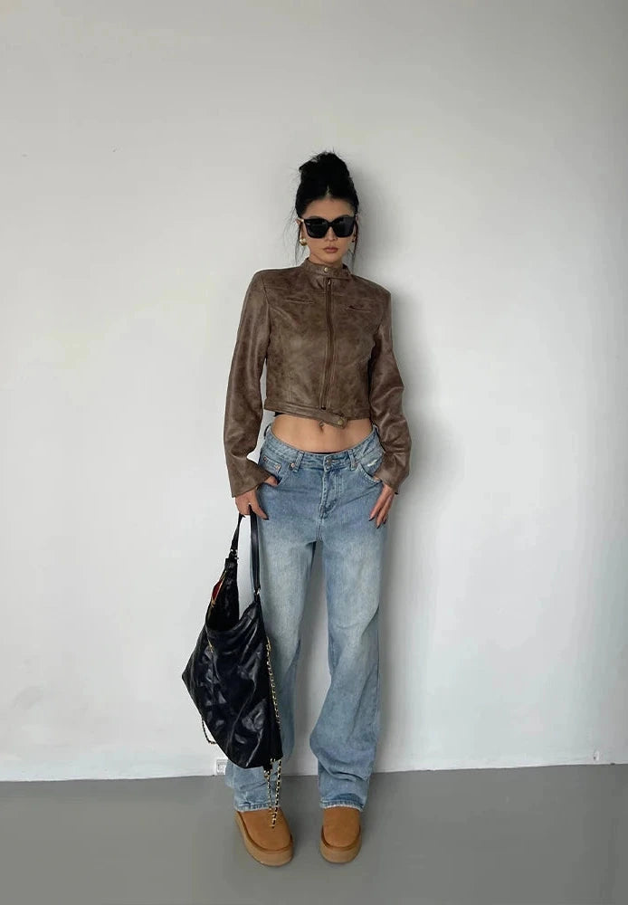 Black stand collar leather jacket with zip closure and side pockets displayed on a wooden hanger.