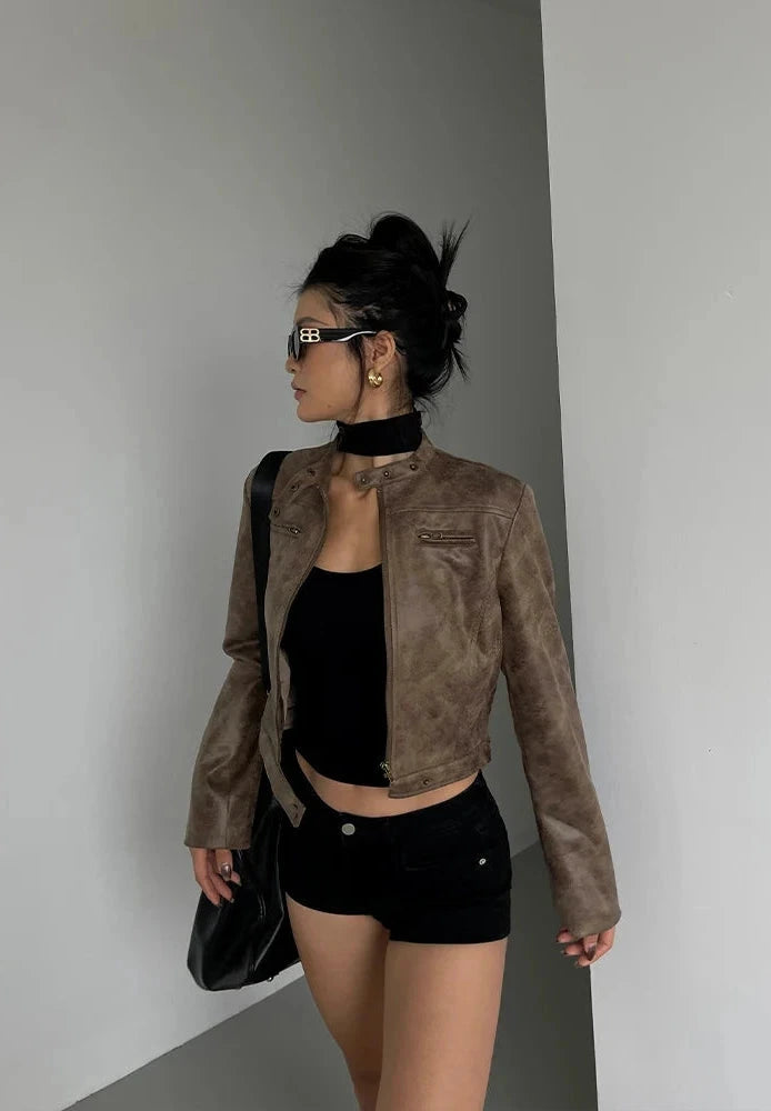 Black stand collar leather jacket with zip closure and side pockets, displayed on a wooden hanger against a neutral background.