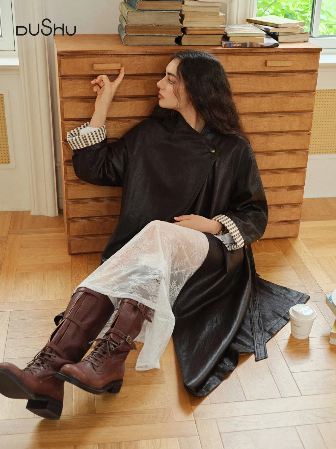 Elegant long overcoat in faux leather with a stand-up collar and belted closure, suitable for casual and formal wear.