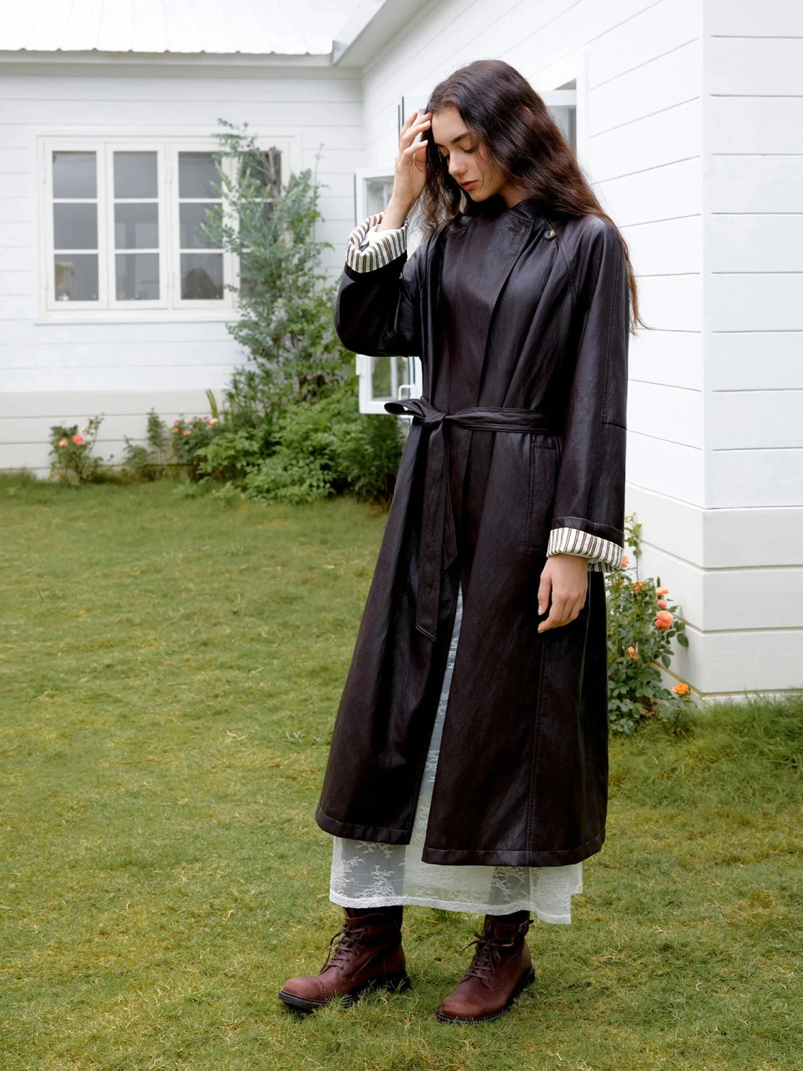 Elegant long overcoat in faux leather with a stand-up collar and belted closure, suitable for casual and formal wear.