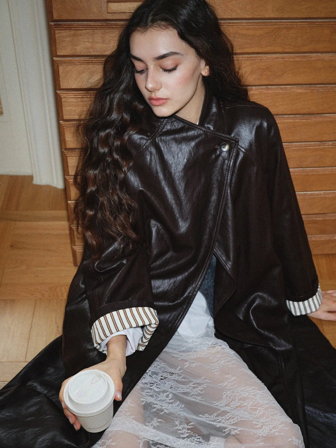 Elegant long overcoat in faux leather with a stand-up collar and belted closure, suitable for casual and formal wear.