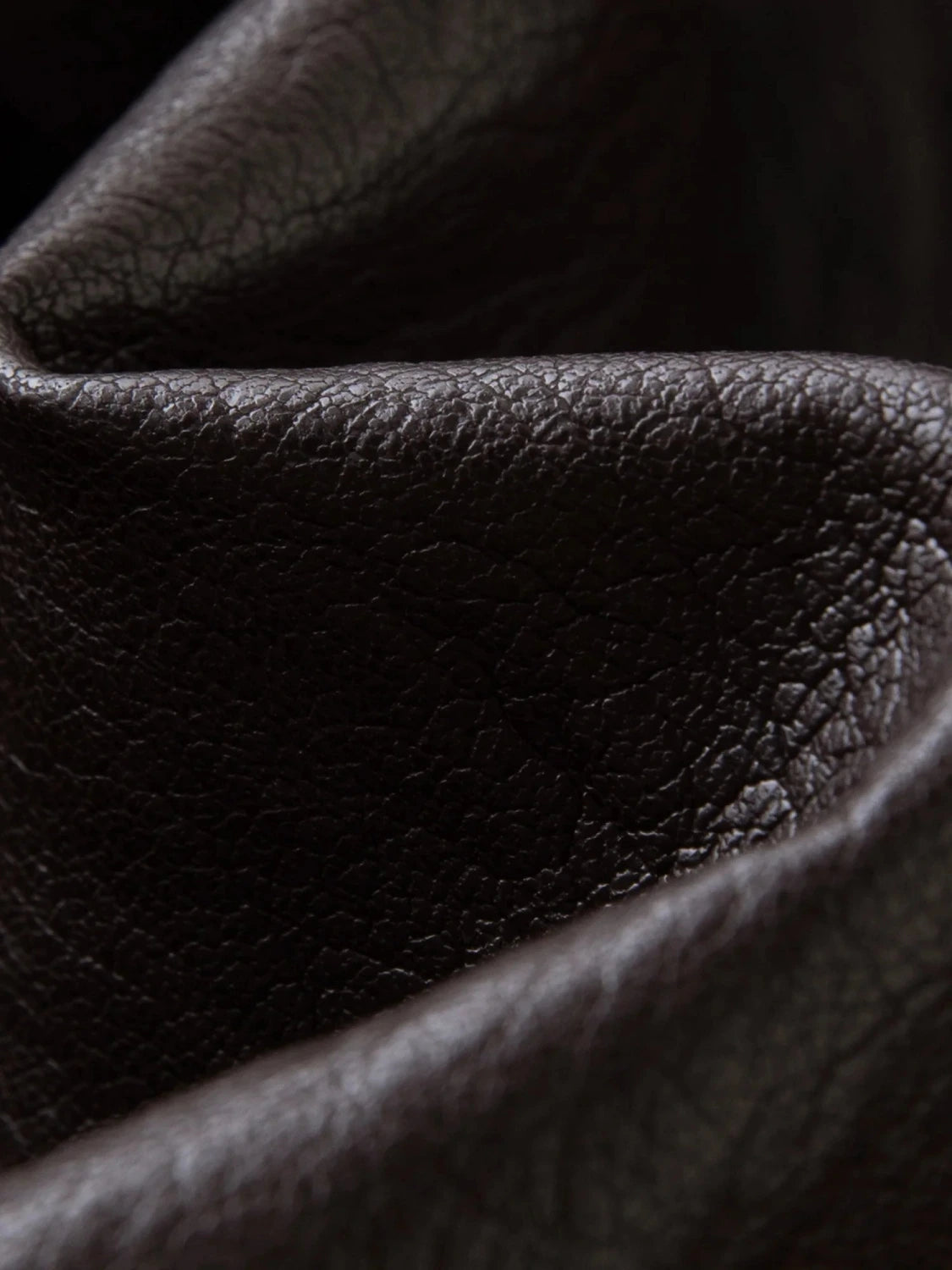 Elegant long overcoat in faux leather with a stand-up collar and belted closure, suitable for casual and formal wear.