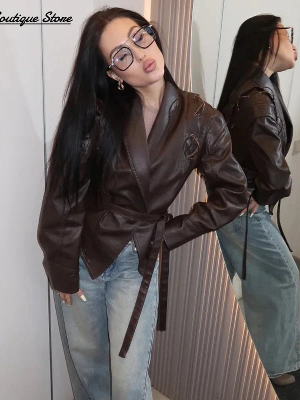 Vintage brown leather jacket with padded shoulders, belt closure, pockets, and turn-down collar. Regular length and tailored