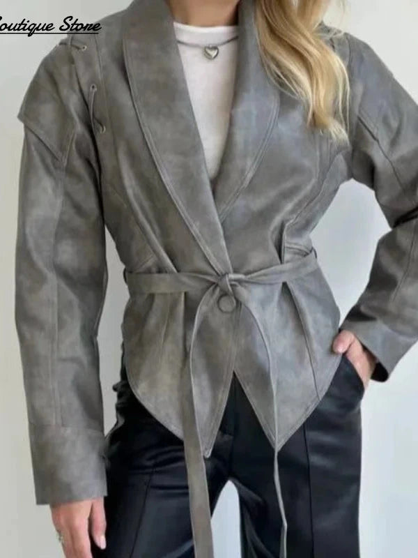 Vintage brown leather jacket with padded shoulders, belt closure, pockets, and turn-down collar. Regular length, tailored fit