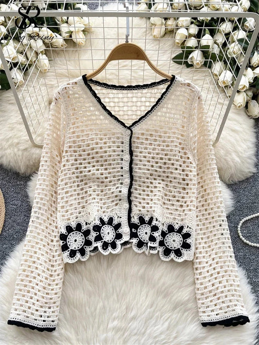 Chic knitted cardigan with floral hollow design and button closure, featuring full sleeves and a loose fit.