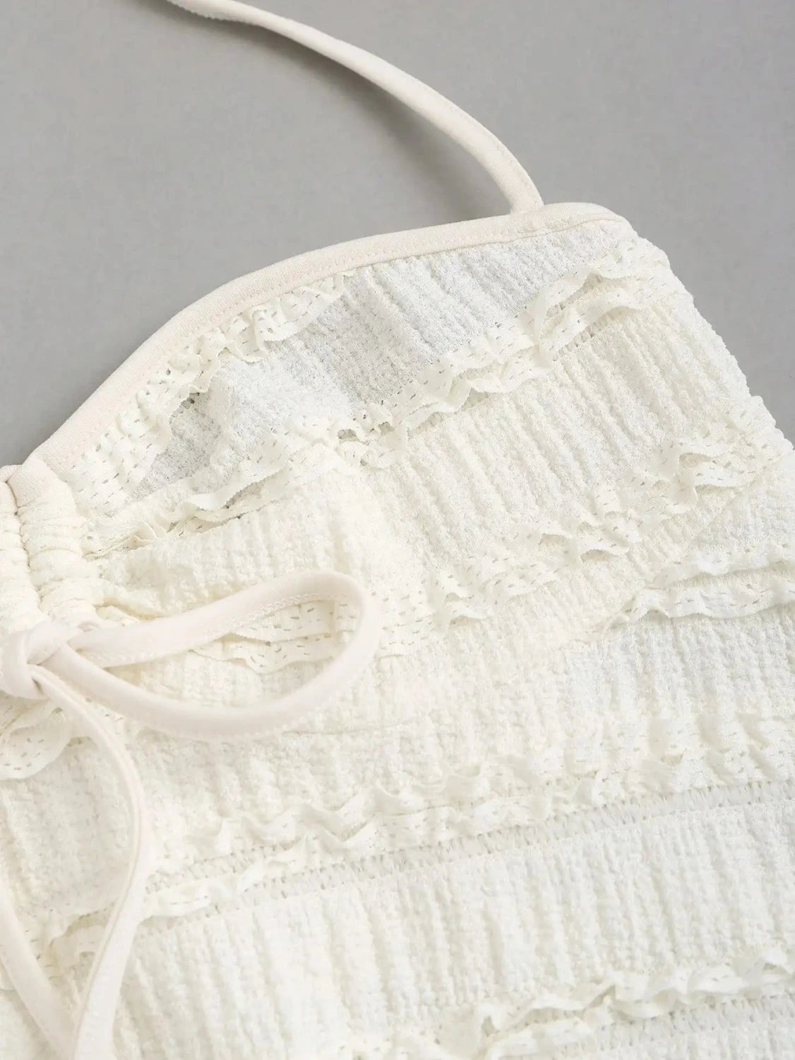 Textured halter neck knitted vest top with drawstring detail and backless design in a soft apricot hue.