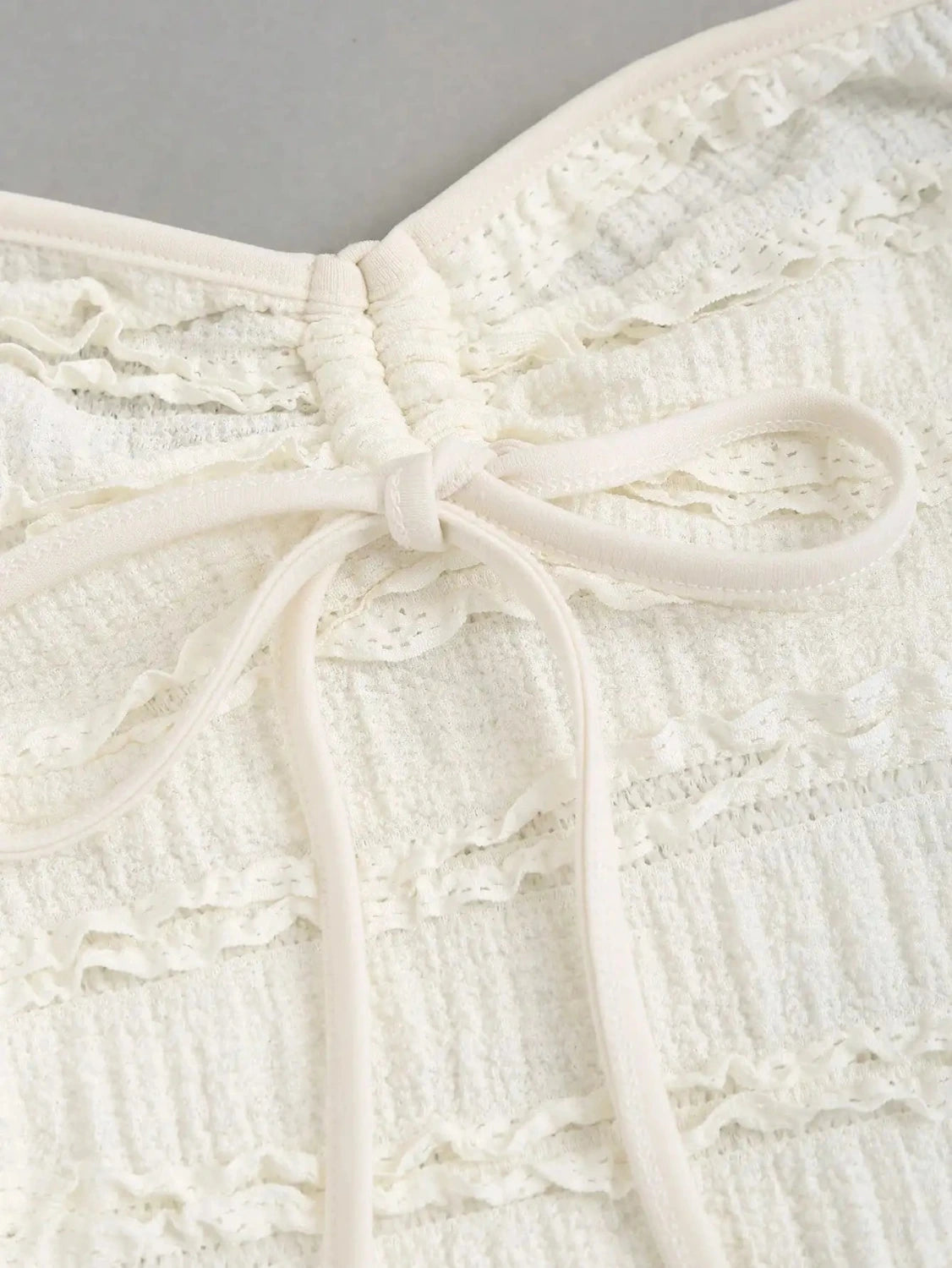 Textured halter neck knitted vest top with drawstring detail and backless design in soft apricot hue.